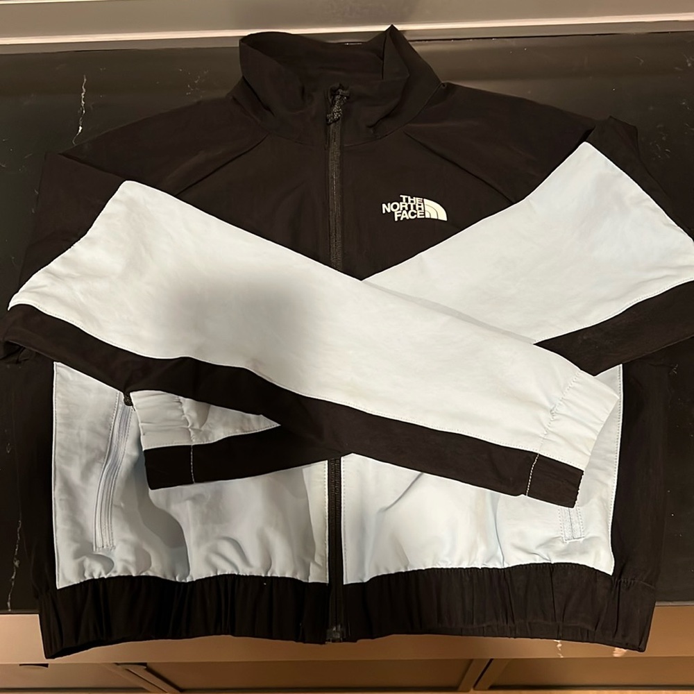 The North Face Cropped windbreaker in light blue and black. Size Medium